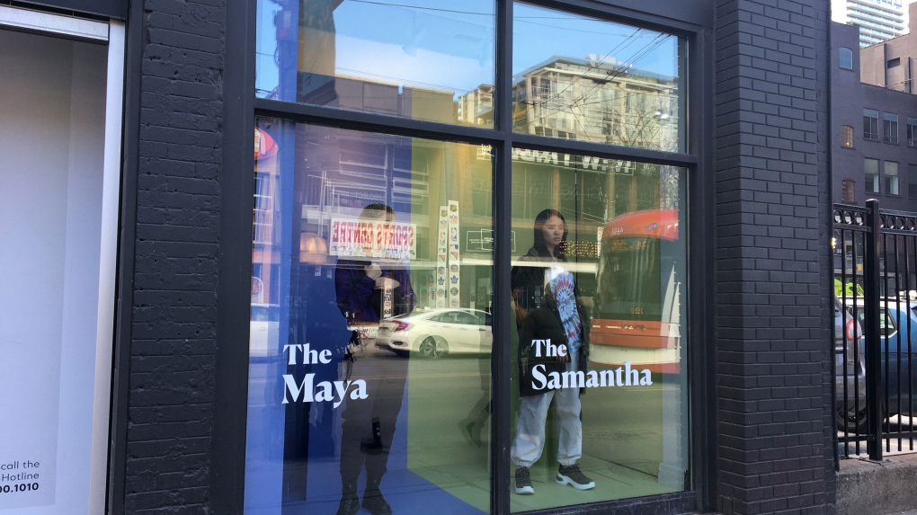 Models pose at a Toronto store front window to simulate how victims are seen as profitable items