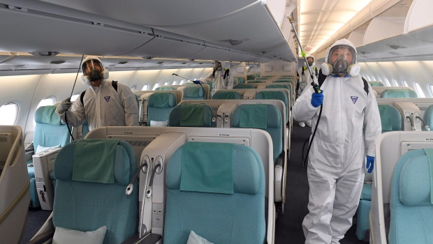 Workers wearing protective suits spray disinfectant inside the airplane for New York as a precaution against the new coronavirus at the Incheon International Airport in Incheon, South Korea, Wednesday, March 4, 2020. the coronavirus epidemic shifted increasingly westward toward the Middle East, Europe and the United States on Tuesday, with governments taking emergency steps to ease shortages of masks and other supplies for front-line doctors and nurses. (Suh Myoung-geon/Yonhap via AP)