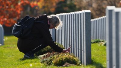 A lady takes a moment as she visits a gravesite during Remembrance Day services at the National Military Cemetery in Ottawa on Thursday, Nov. 11, 2021. (Sean Kilpatrick/THE CANADIAN PRESS)