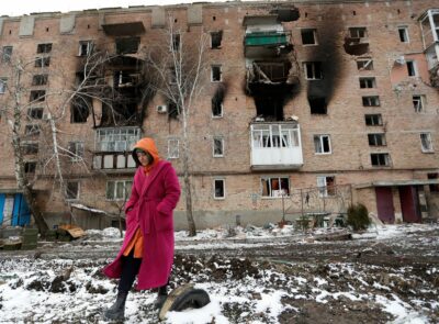 زنی در شهر ولنوواخا در منطقه دونتسک اوکراین که تحت کنترل جدایی طلبان است مقابل یک ساختمان مسکونی آسیب دیده راه می رود. 11 مارس 2022